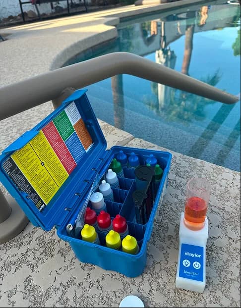 Pool water testing kit with reagents on pool deck