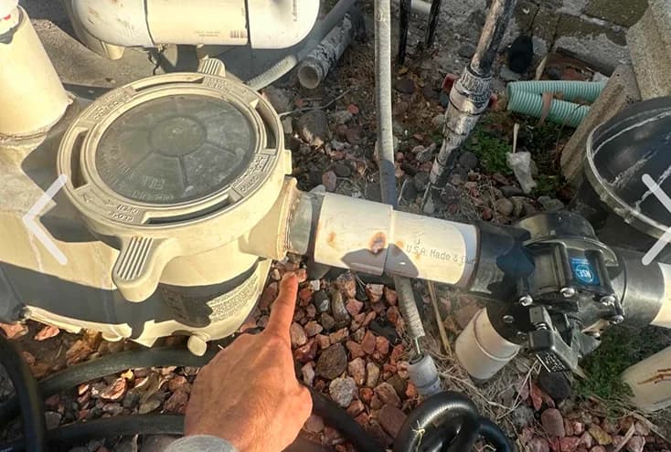 Technician inspecting pool pump plumbing union and valve